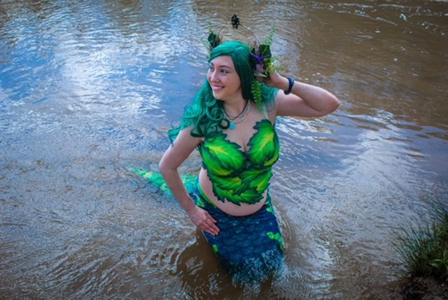 Green-haired mermaid kneeling in a sparkling river